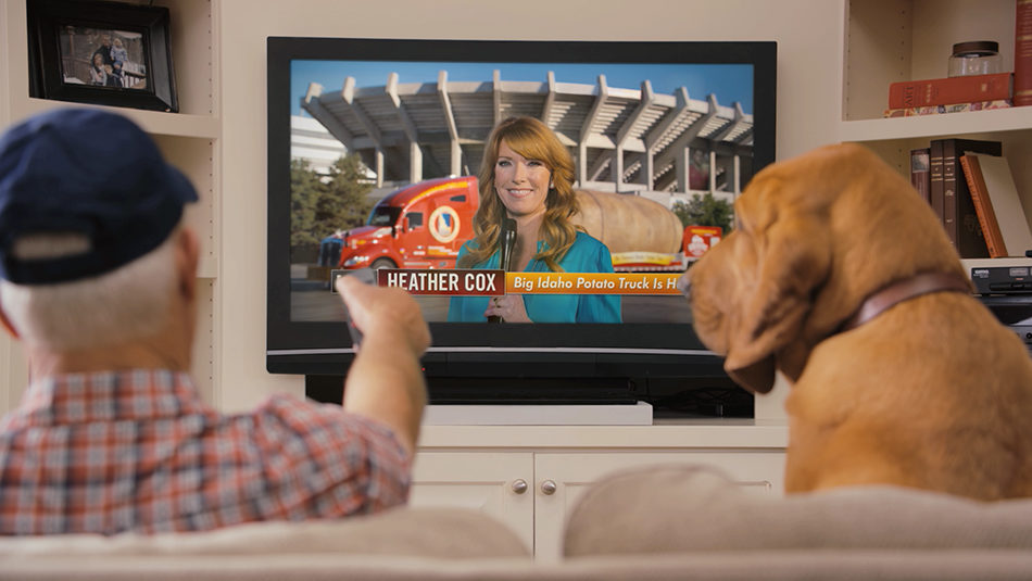 Idaho Potato Farmer in blue hat with dog sitting on couch watching TV of EvansHardy+Young Commercial