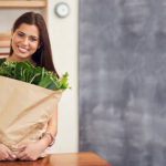 Woman holding brown bag of produce