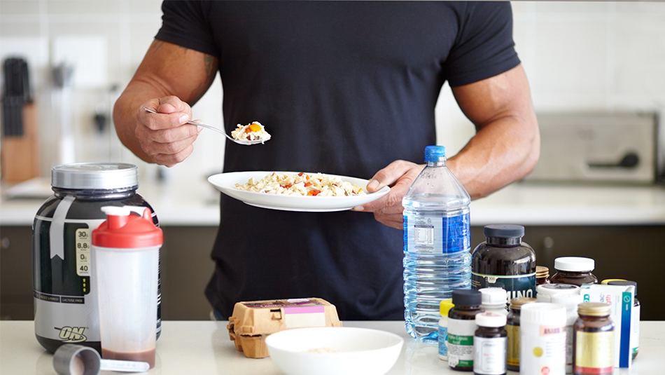 Athlete eating bowl of oatmeal with eggs, supplements and protein powder in front of him