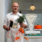 Butcher in shop holding cleaver and carrots