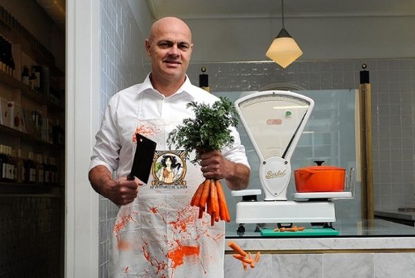 Butcher in shop holding cleaver and carrots