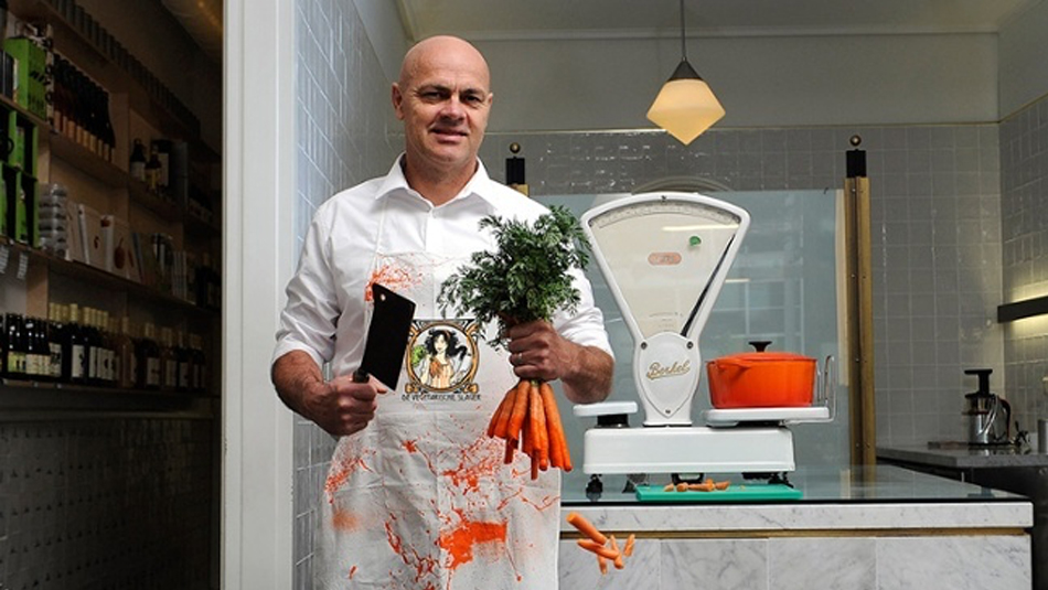 Butcher in shop holding cleaver and carrots