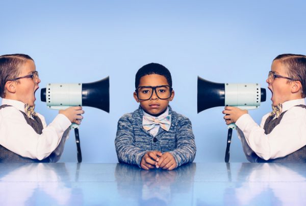 Two professional kids yelling with bullhorns at middle kid on light blue background