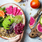 hands holding plate of plant based foods