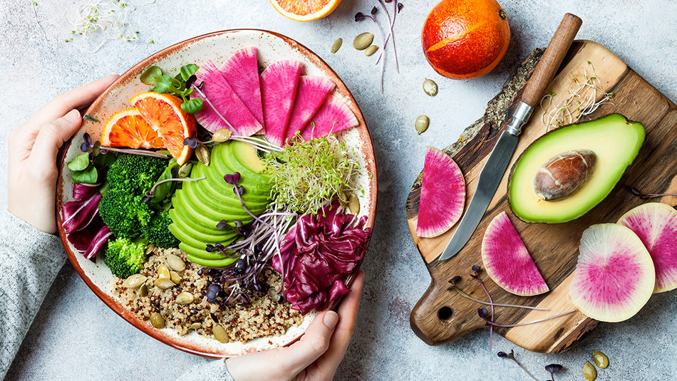 hands holding plate of plant based foods