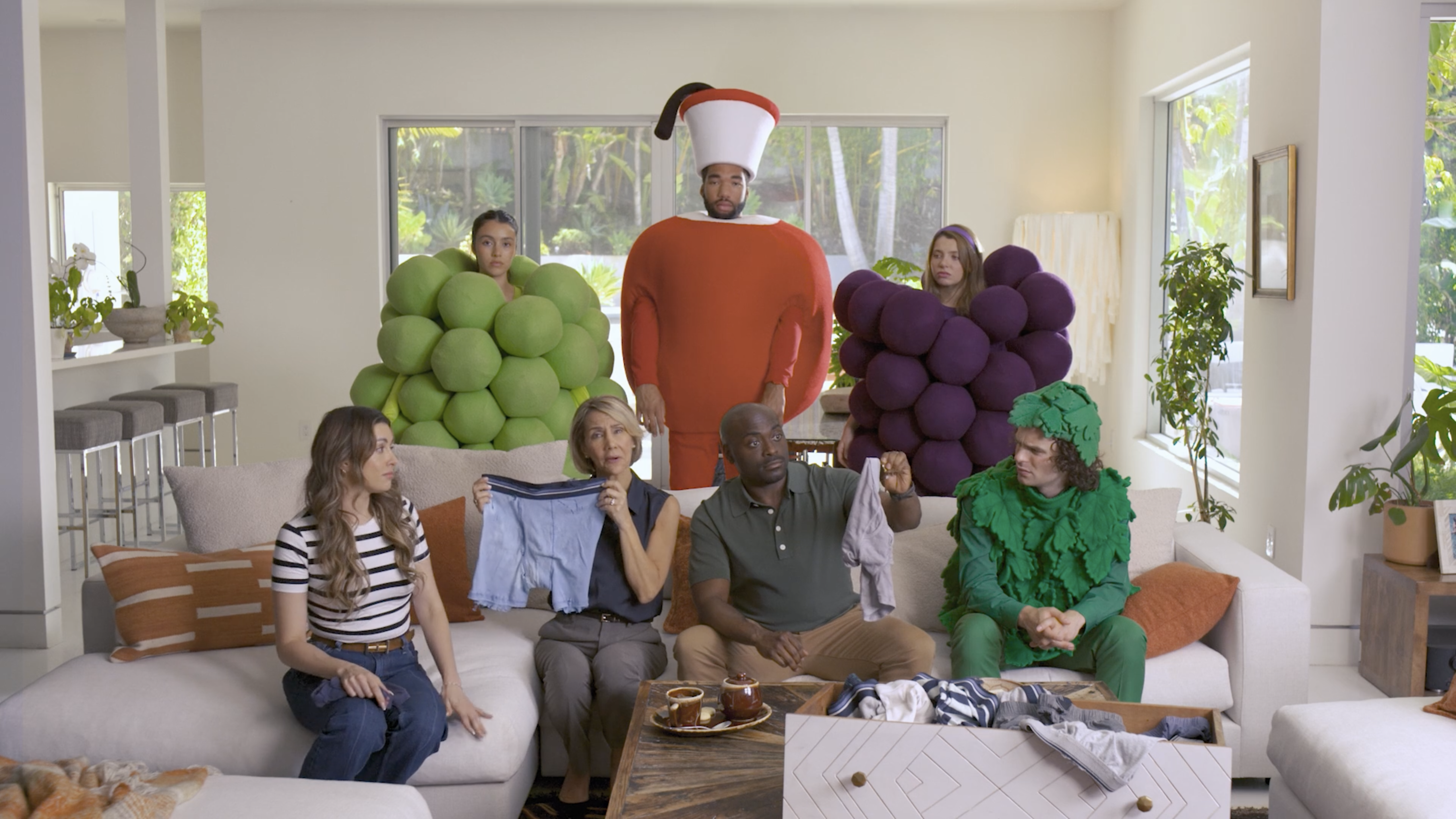 A group of people dressed as grapes in a living room, promoting food and branded products for a marketing agency.